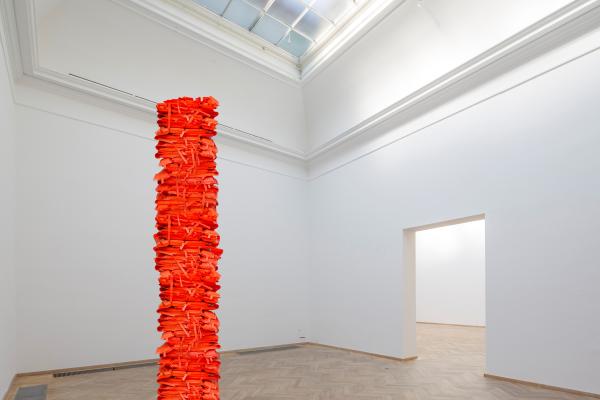 Photograph of a pillar made of stacked bright orange life jackets