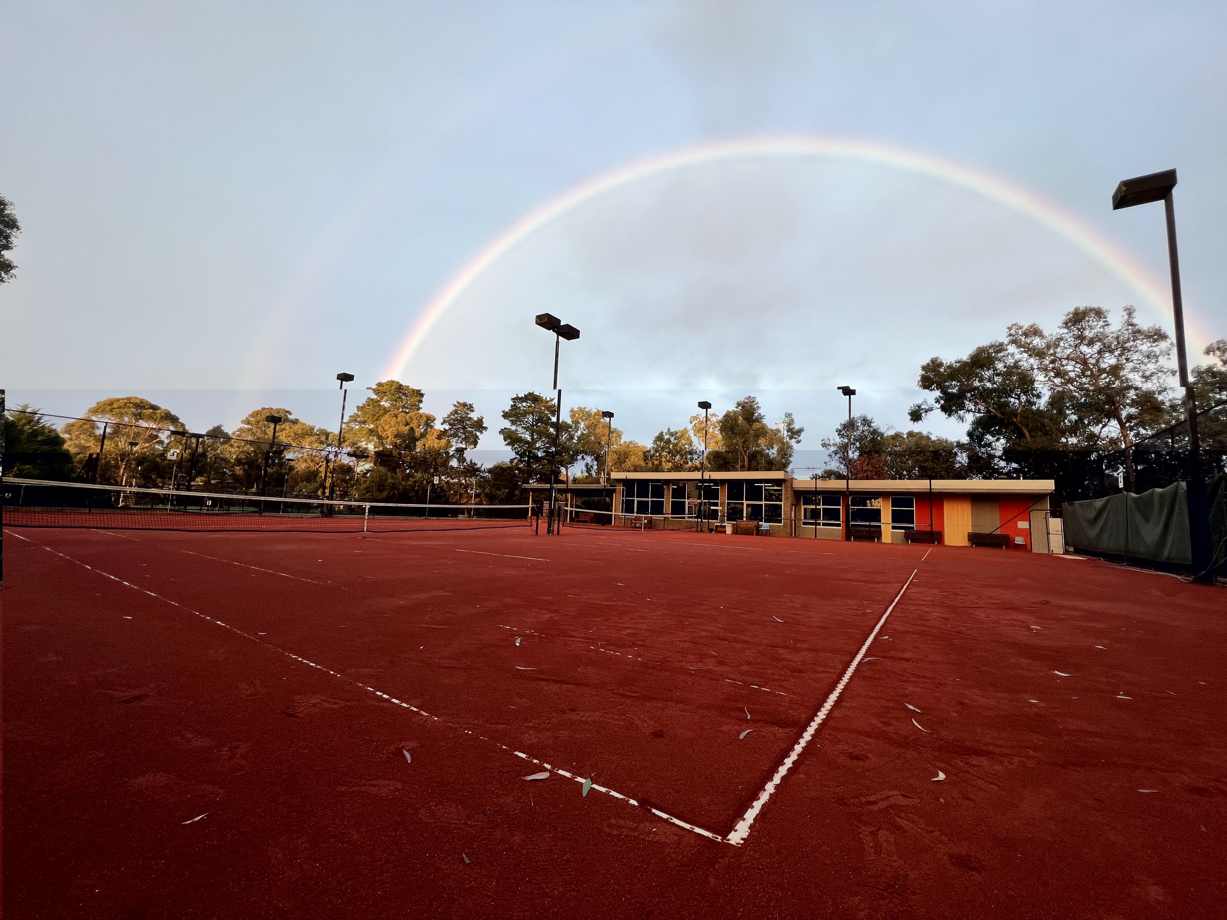 Rainbow over a clay tennis court