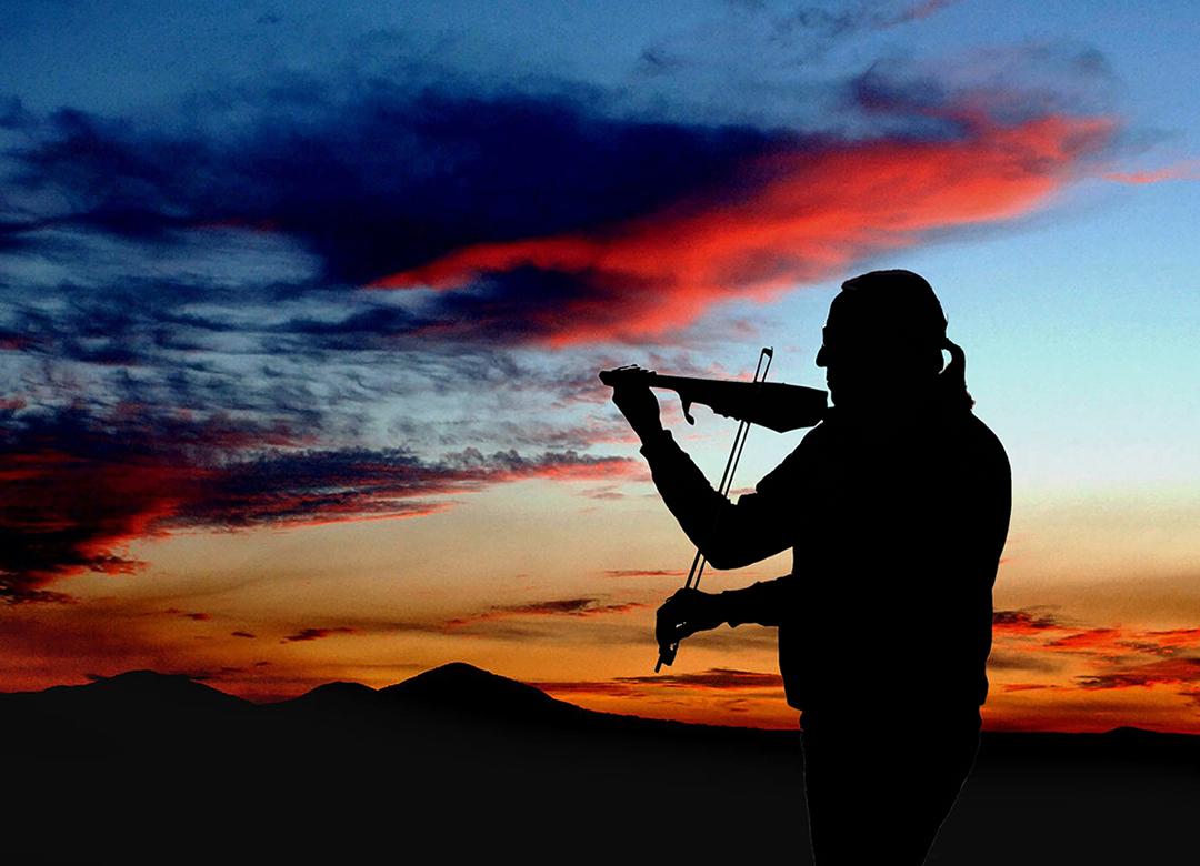 Violinist Michael Doyle in silhouette in front of sunset