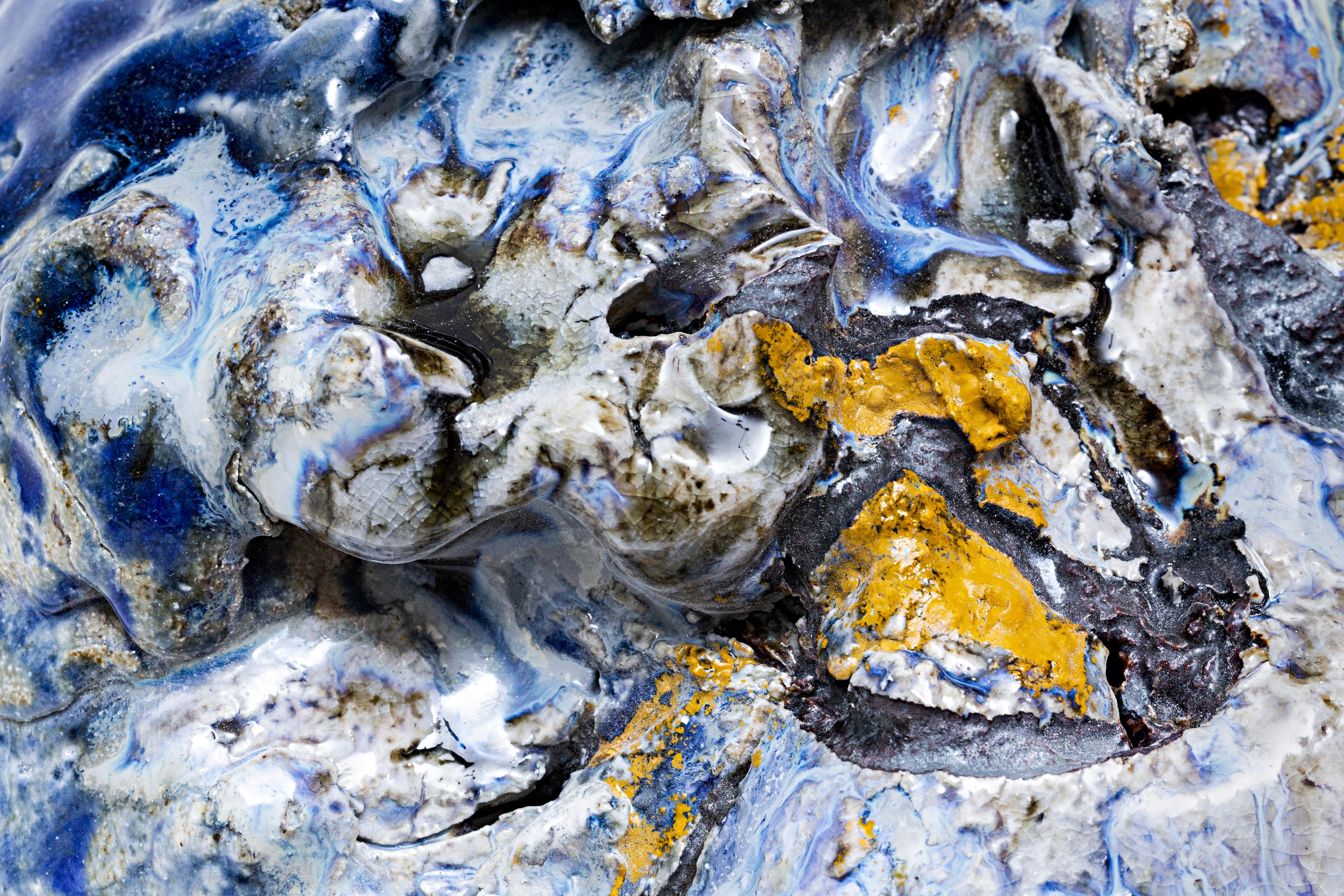 Detailed photograph of blue and yellow glazes on a textured ceramic surface