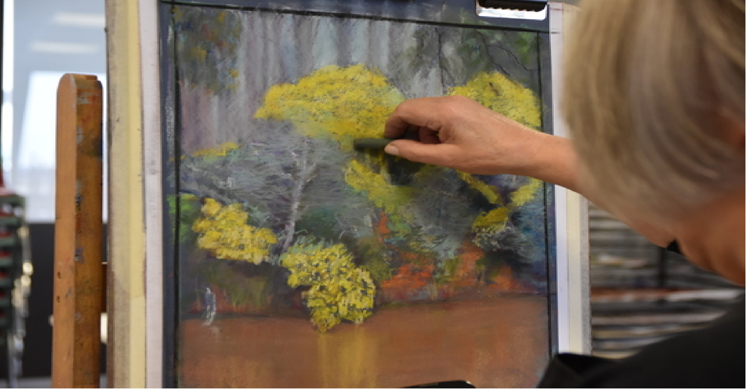 photo of a person sketching a landscape with yellow flowers and foliage in pastel