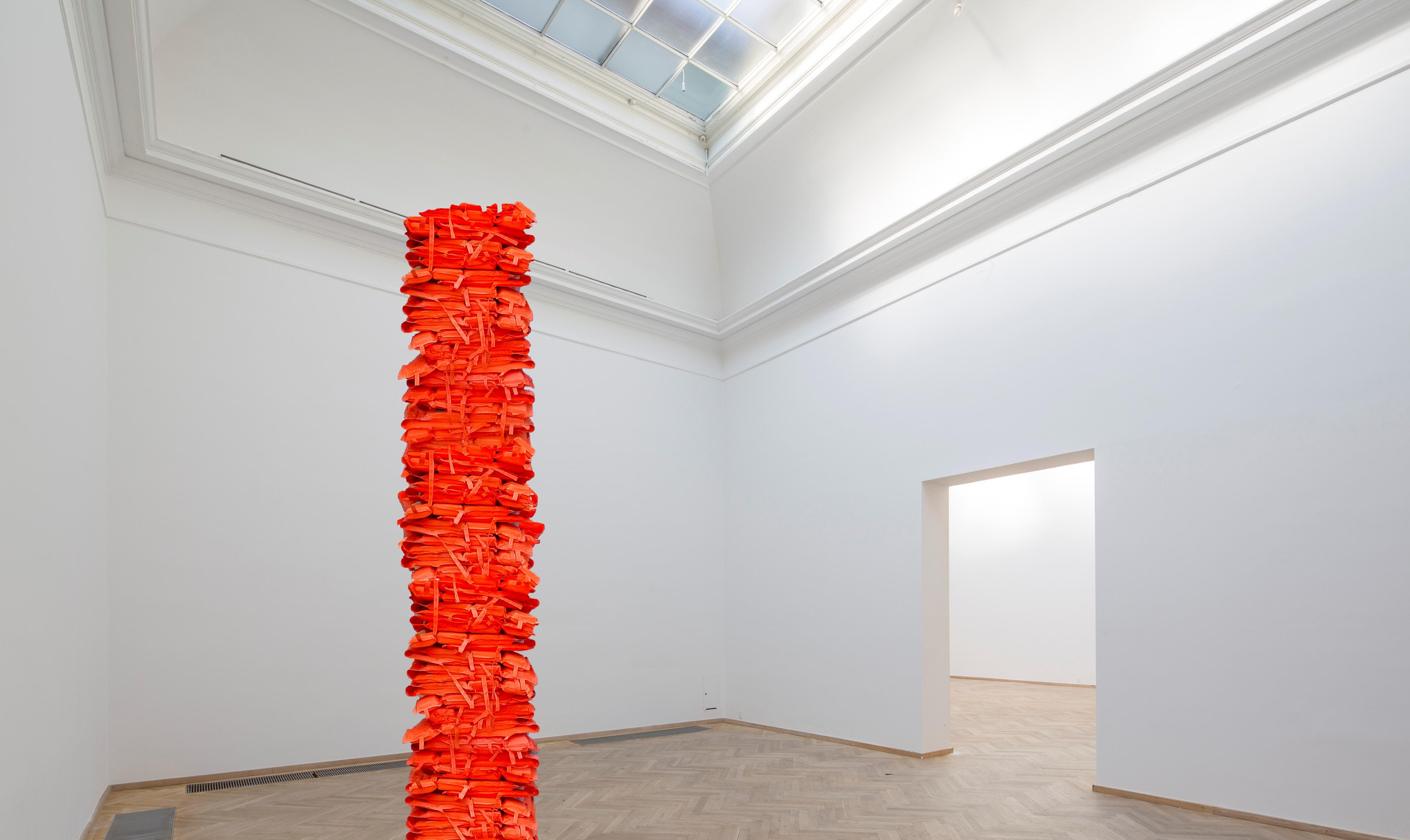 Photograph of a pillar made of stacked bright orange life jackets
