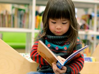 young girl reading book in library