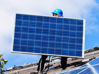 Man placing a solar panel on a roof