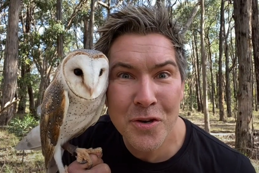 Man with native owl on shoulder looking directly at camera