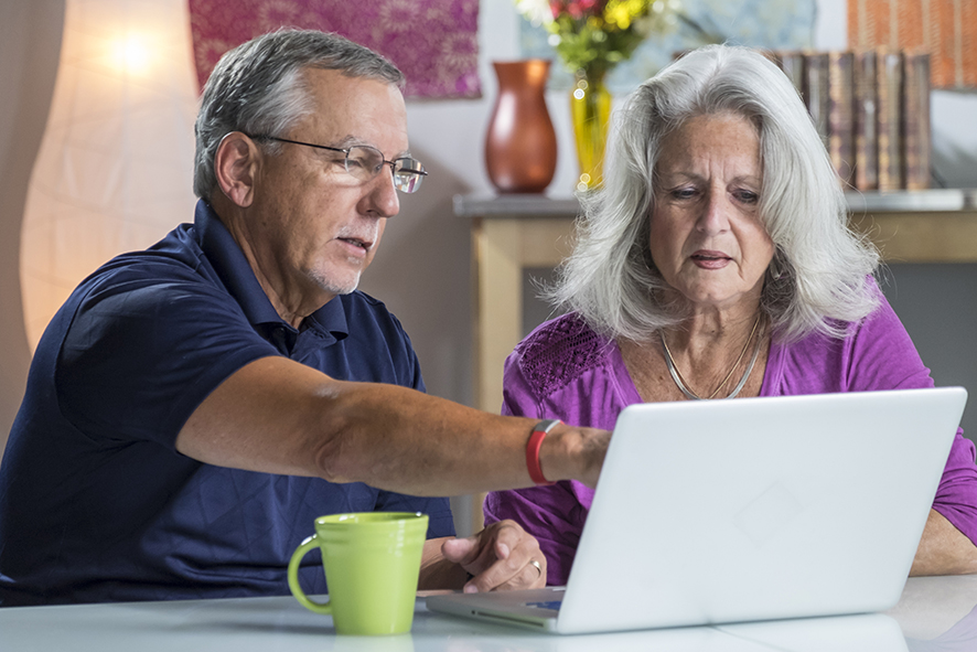 concerned senior couple looking at laptop screen