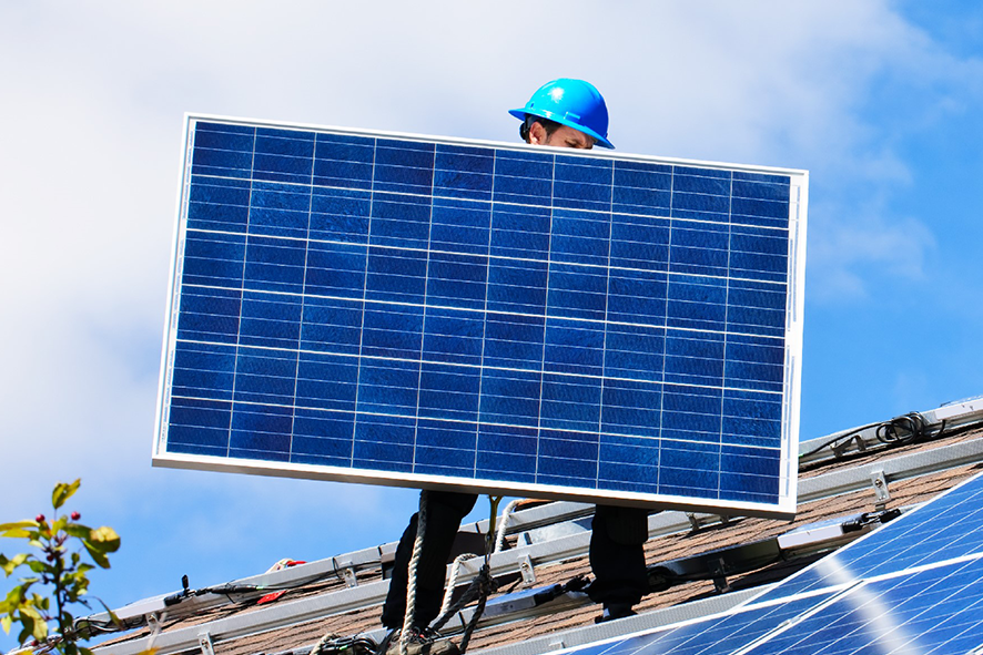 Man placing a solar panel on a roof